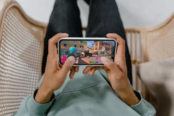 Hands using PuK magnetic trigger accessory while playing Fortnite on smartphone